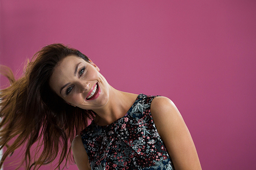 Smiling woman tossing her long hair against purple background