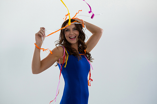 Smiling woman wrapped in multi color streamers posing against white background
