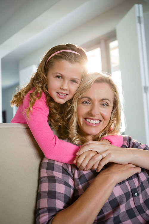 Portrait of mother and daughter embracing each other in the living room at home
