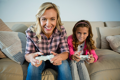 Mother and daughter playing video game in the living room at home