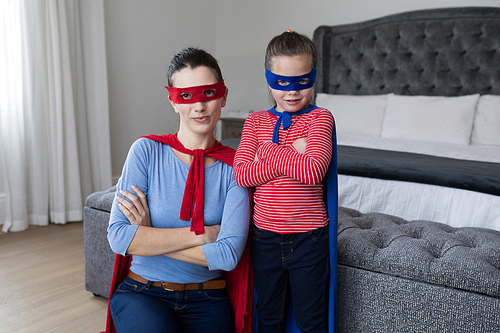 Portrait of Mother and daughter pretending to be superhero in bedroom