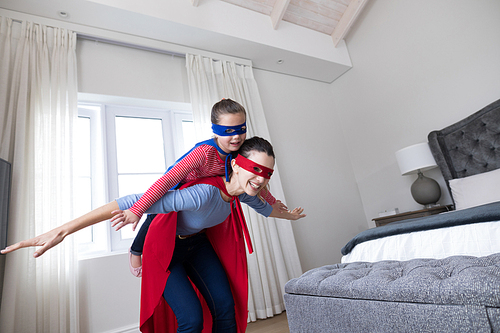 Mother and daughter pretending to be superhero in bedroom
