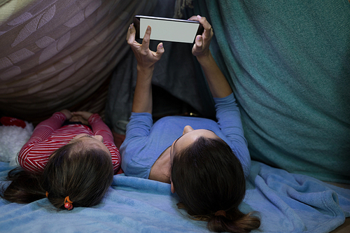 Mother and daughter using digital tablet while relaxing at home