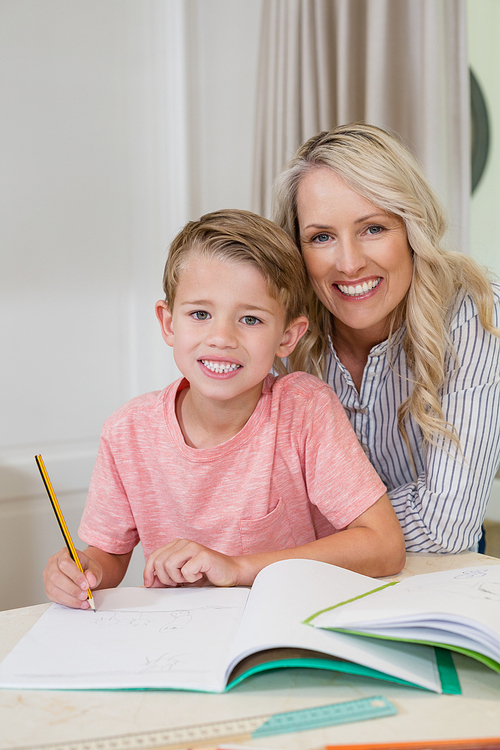 Portrait of mother assisting son doing homework at home