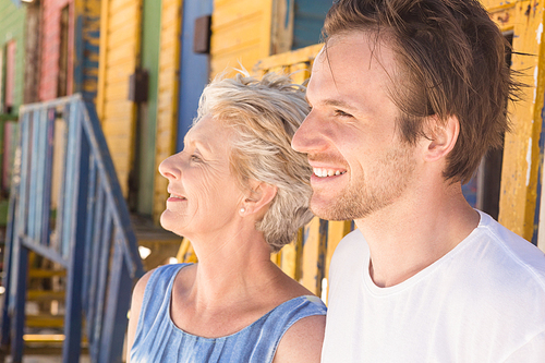 Close up of man with mother looking away while standing against beach hut