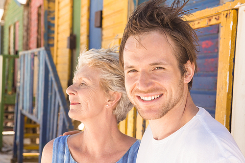 Portrait of cheerful man with mother standing against beach hut