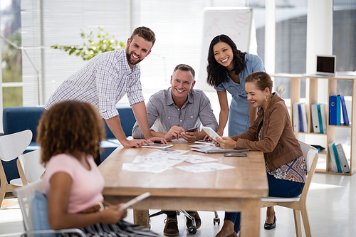 Smiling team of executives interacting with each other while working in the office