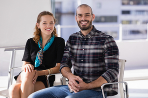 Portrait of happy colleagues sitting on chair in office