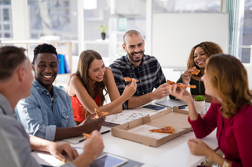 Group of executives interacting while having pizza in conference room