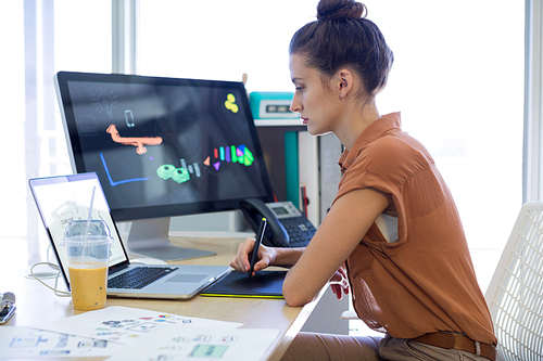 Female executive working over graphic tablet at her desk in office