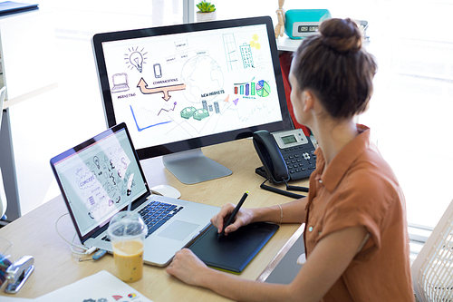 Female executive working over graphic tablet at her desk in office