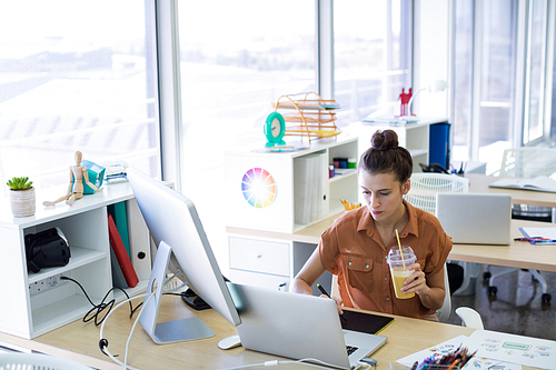 Female executive working over graphic tablet at her desk in office