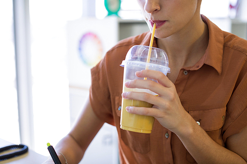 Close-up of female executive having drink while working at her desk in office