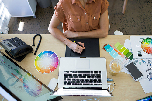 Female executive working over graphic tablet at her desk in office