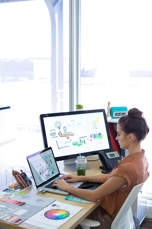 Female executive working over laptop at her desk in office