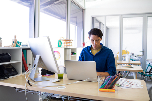 Male executive working over laptop at his desk in office