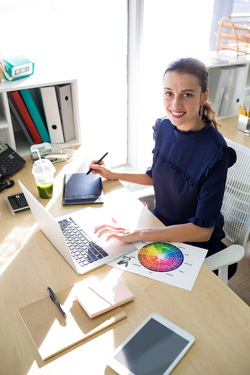 Portrait of female executive working over graphic tablet at her desk in office