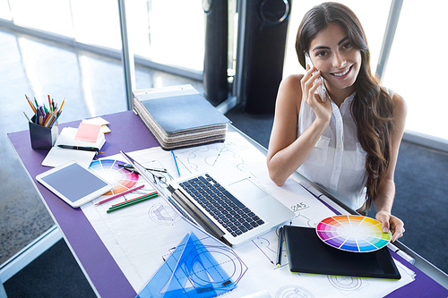 Female executive talking on mobile phone at her desk in office