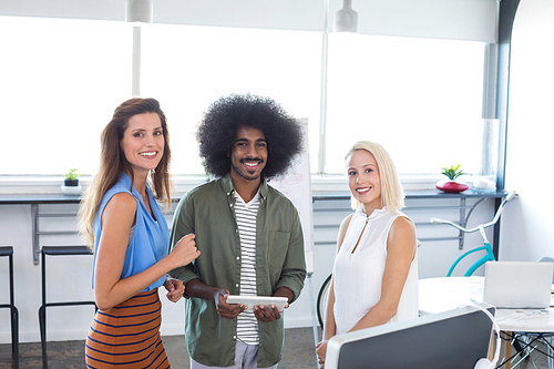 Portrait of executives discussing over digital tablet in office