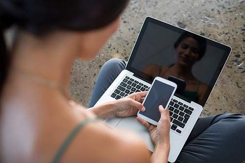 Close-up of female executive using laptop and mobile phone in office