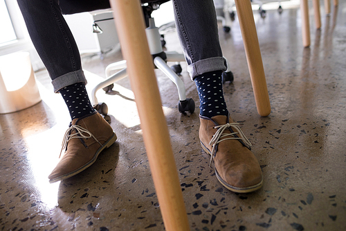 Low section of male executive relaxing on chair in office