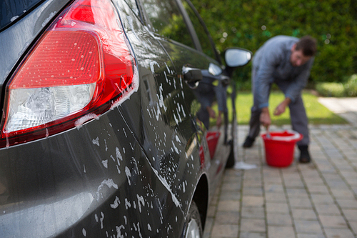 Male auto service staff washing a car