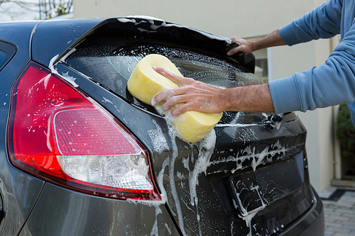 Male auto service staff washing a car with sponge