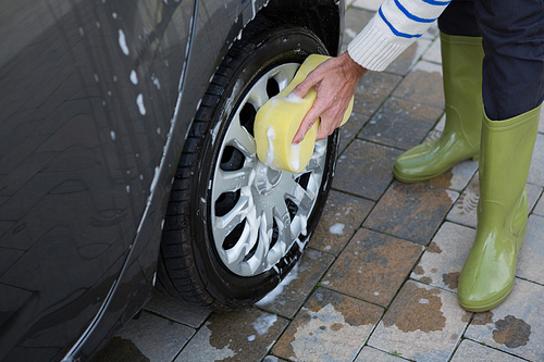 Male auto service staff washing a car with sponge