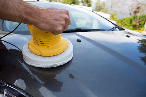 Male auto service staff cleaning a car bonnet with rotating wash brush