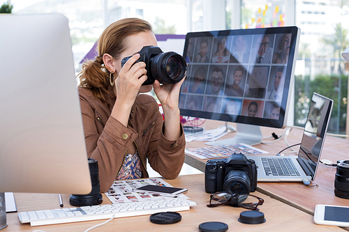 Female executive taking a photograph from digital camera in office