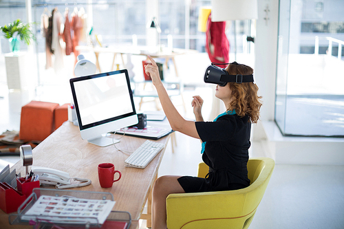 Female designer using virtual reality headset in office