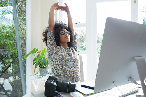 Graphic designer stretching her arms at desk