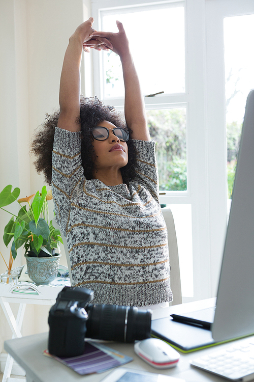 Graphic designer stretching her arms at desk