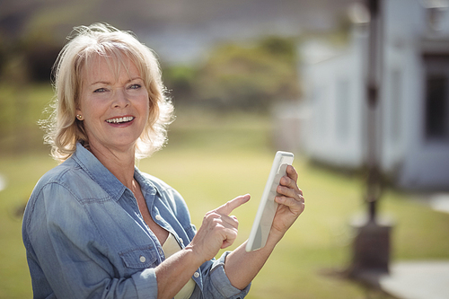 Portrait of smiling senior woman using digital tablet on a sunny day