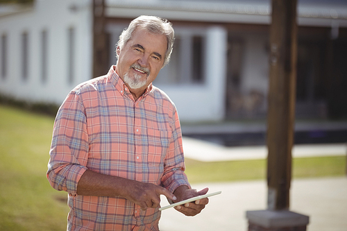 Smiling senior man using digital tablet on a sunny day