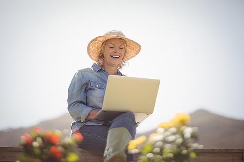 Smiling senior woman using laptop in park on a sunny day