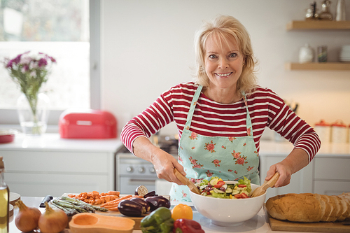 Portrait of senior woman preparing meal in kitchen