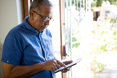 Senior man using digital tablet by window at nursing home