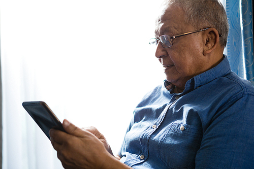 Senior man using tablet by window at nursing home