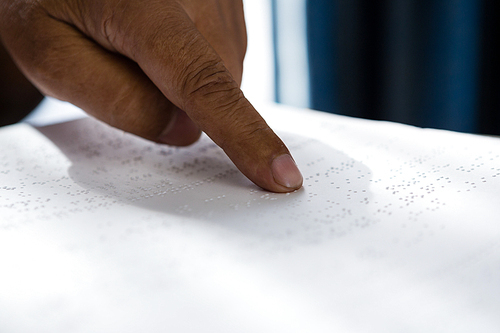 Cropped hand on senior man reading braille book in retirement home