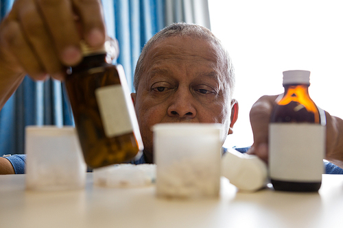 Senior man taking medicines at table in nursing home