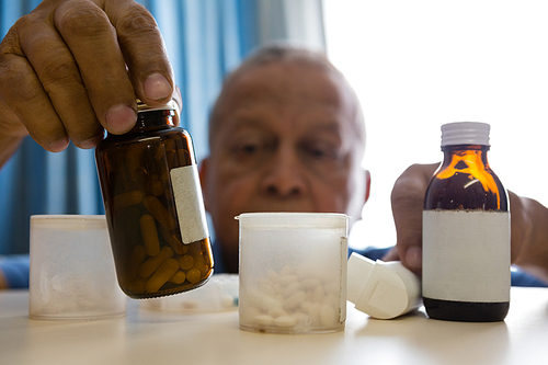Senior man taking medicines at table in retirement home