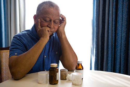 Thoughtful senior man looking at medicines in retirement home