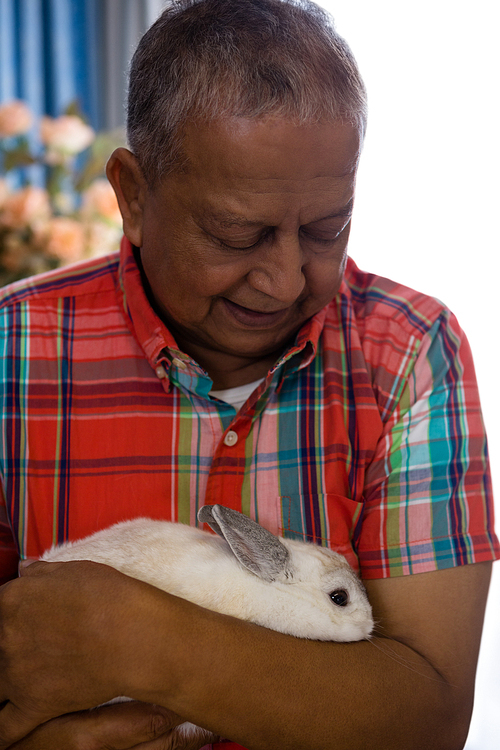 Close up senior man holding rabbit at retirement home