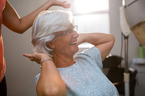 Midsection of hairstylist standing by happy senior woman at salon