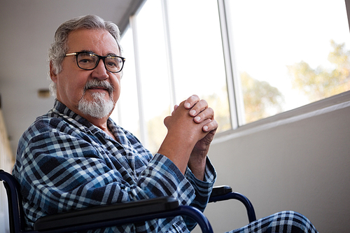 portrait of senior man sitting on . by window in retirement home