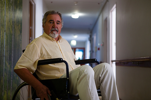 portrait of senior man sitting on . in corridor at retirement home