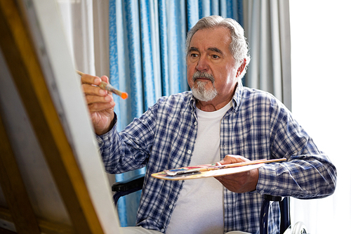 senior man painting while sitting on . in nursing home