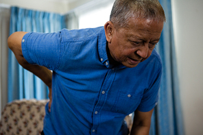 Close up of senior man holding back while standing in nursing home