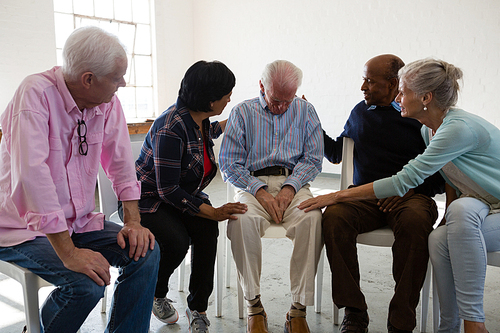 Senior friends consoling male friend during discussion in art claa